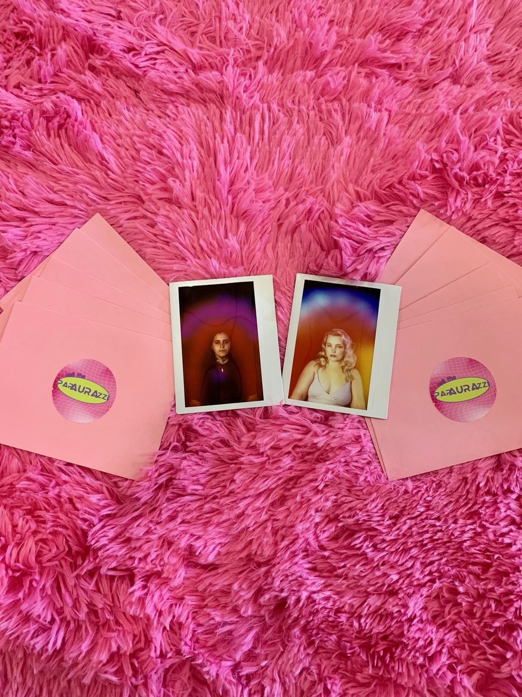 Two aura portraits with pink Call the Papaurazzi envelopes on a bright pink rug.